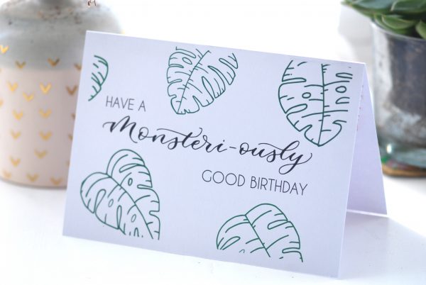 White card with hand drawn monstera leavesand text that says "Have a monster-iously good birthday"