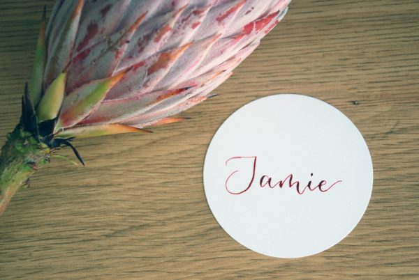 White circular disc event table setting with name handwritten in pink ink in calligraphy