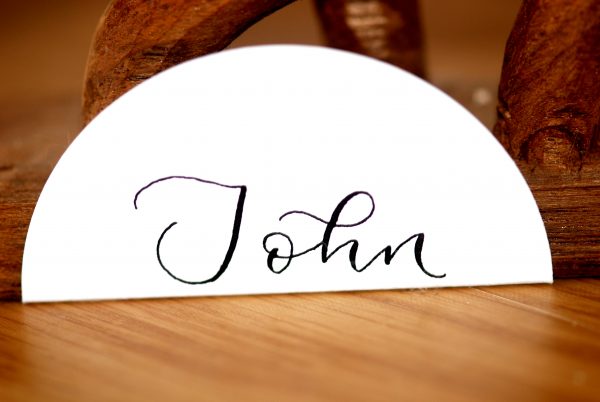 White folding disc place setting with name in calligraphy for event