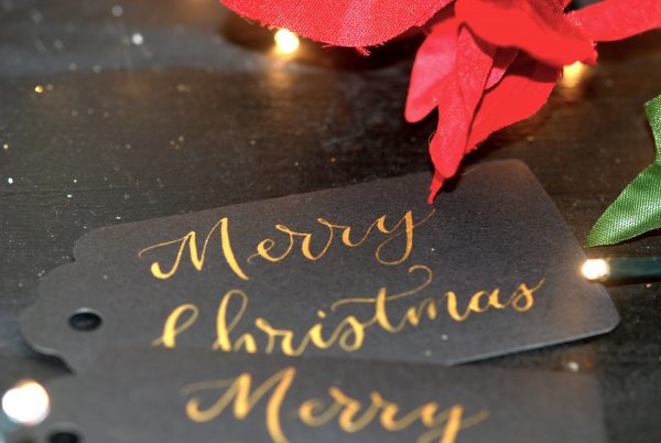 Black card gift tags with Merry Christmas written in gold ink and calligraphy